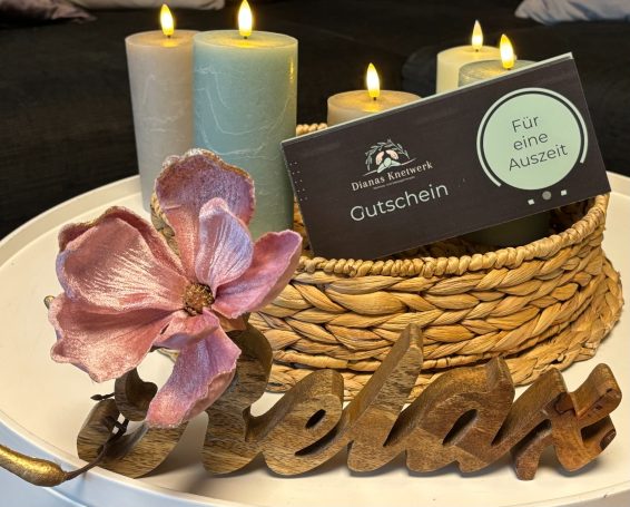 Ein Dekorationsarrangement mit Kerzen, einem Gutschein und einer Blume mit dem Wort "Relax".