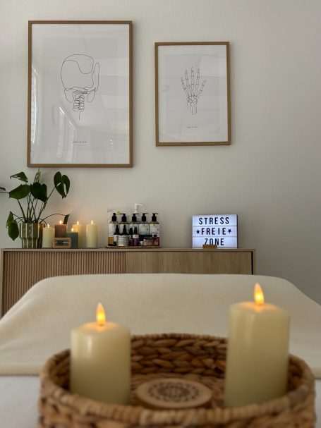 Beleuchtete Kerzen und Kunstwerke auf einer hellen Wand, mit einem Holztisch im Vordergrund.